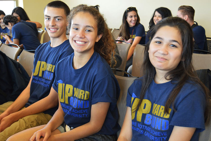 Three students smiling while wearing Upward Bound t-shirts