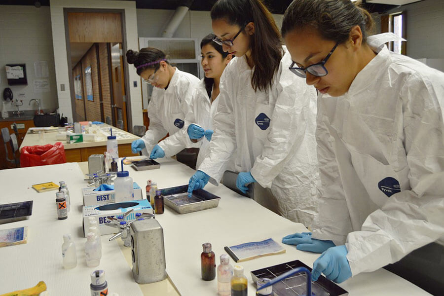 Four students in lab coats working in a laboratory