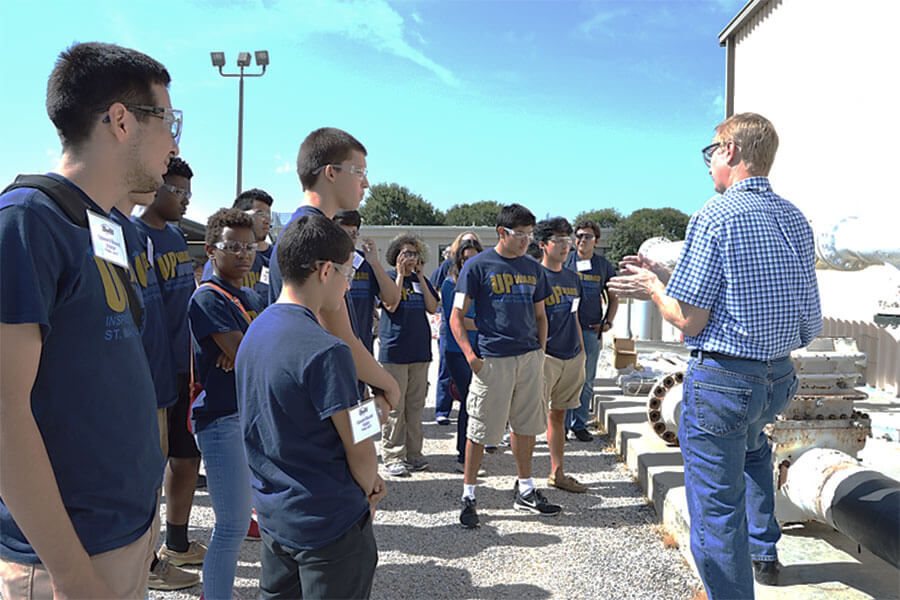 A professor leading a demonstration for Upward Bound students wearing safety glasses