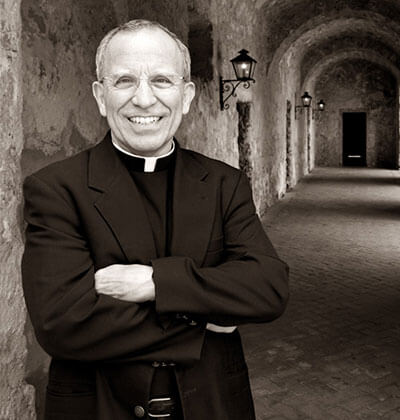 Father David Garcia stands against a wall at one of the Missions.