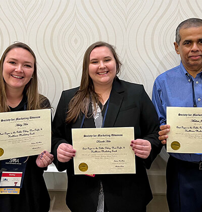 Danielle Hass and Ashley Hass pose with Professor Mathew Joseph, Pd.D., in Orlando, Florida.
