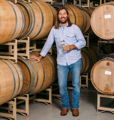 Ron Yates stands next to a wine barrel at one of his businesses.