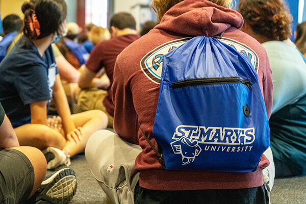 close up from behind of student sitting at orientation wearing a St. Mary's backpack
