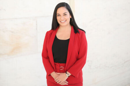 Paulina Vera stands in a red suit.