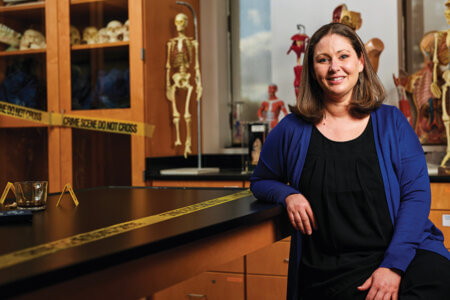 Jennifer Harr, Ph.D., in the Forensic Biotechnology lab, surrounded by crime scene tape and skeletons