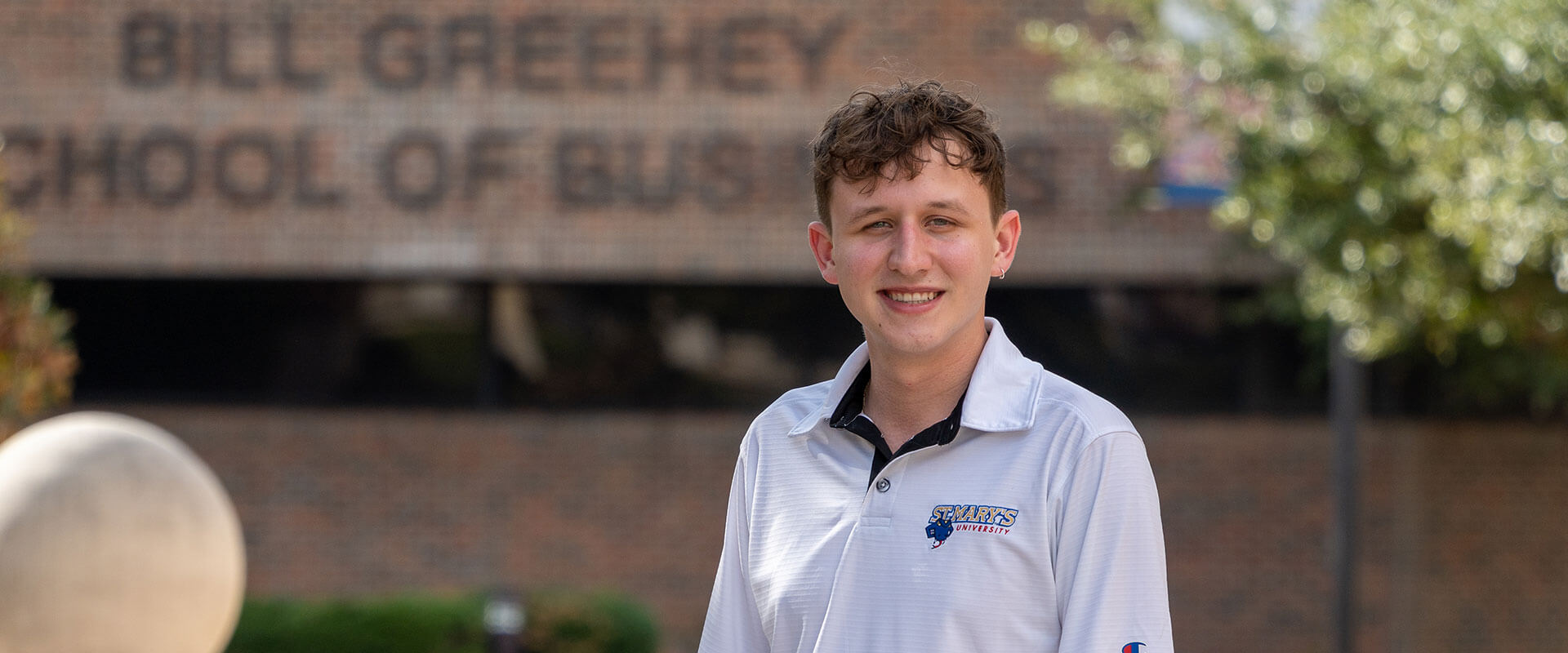 Zane Smith stands in front of the Greehey School of Business.