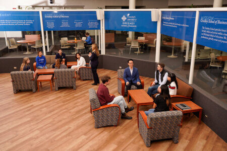Students and teaching staff talk in the atrium of the Alkek building.