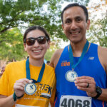 Lucia Martinez and Pete Martinez hold up medals after winning in their 2022 StMU 5K for the neighborhood categories.