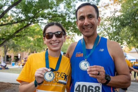 Lucia Martinez and Pete Martinez hold up medals after winning in their 2022 StMU 5K for the neighborhood categories.
