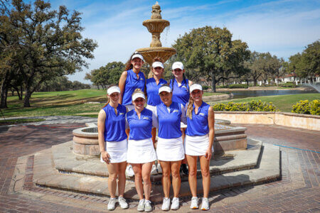 2023 Rattler Women's Golf players stand together by a fountain.