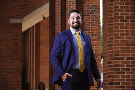 Andrew Tague takes a photo in a suit for earning the President's Award for academic excellence and leadership.