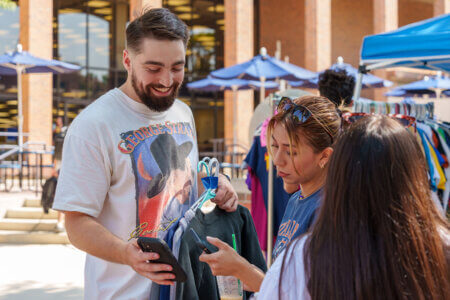 Andrew Tague brings his shop of vintage T-shirts to Rattler Market and visits with shoppers.