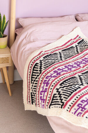 Ashleigh Wempe designs patterns like this pink and purple throw.
