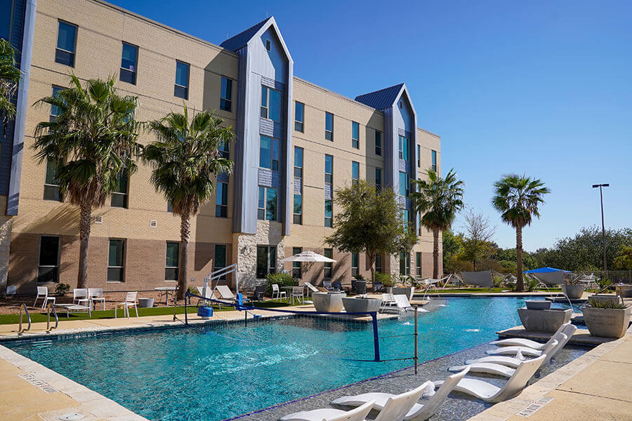 Exterior shot of Périgueux Hall with view of pool and palm trees.