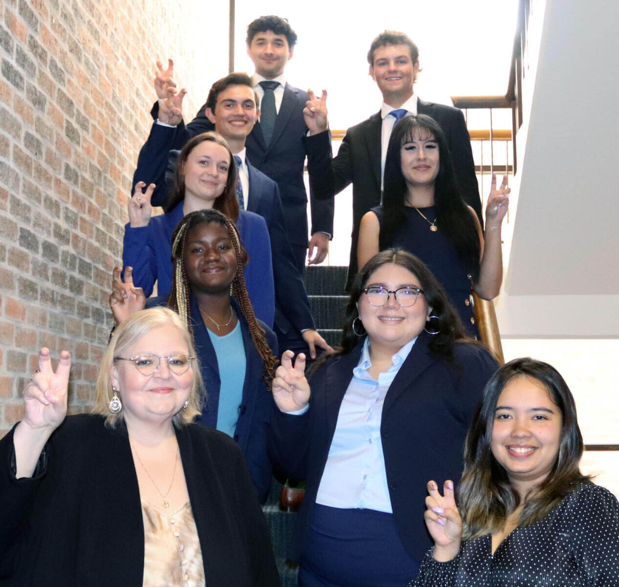 A group of students on a staircase holds up the St. Mary's 'Fangs Out' hand sign.