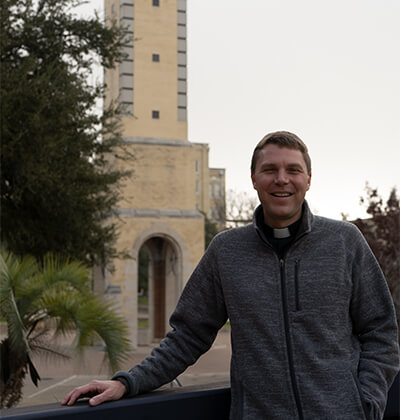 The Rev. Brandon Paluch in front of the Barrett Memorial Bell Tower