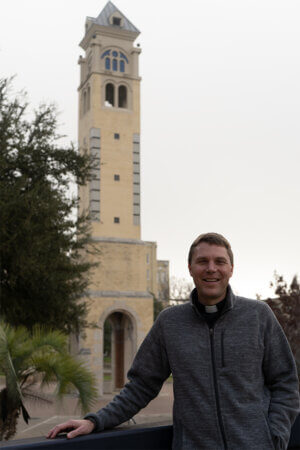 The Rev. Brandon Paluch, S.M., stands in front of the Bell Tower.