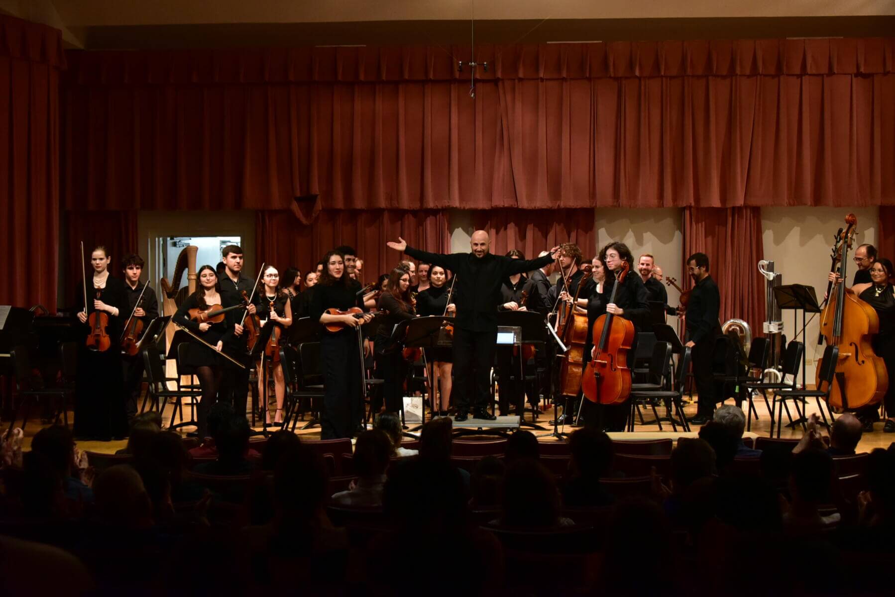 Students holding their musical instruments stands up to take a bow in the Treadaway Recital Hall.