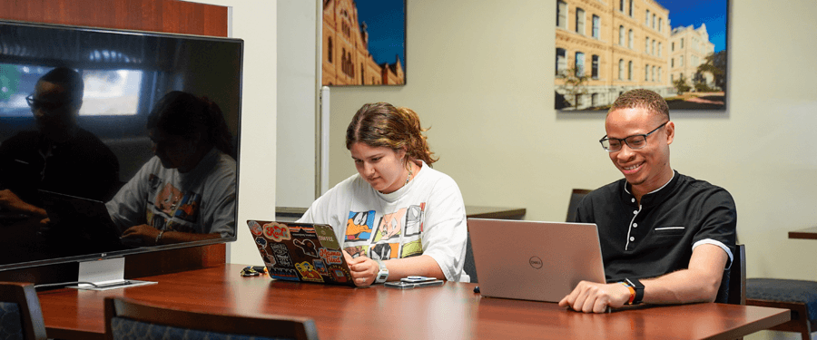 Two Students on campus working on laptops together