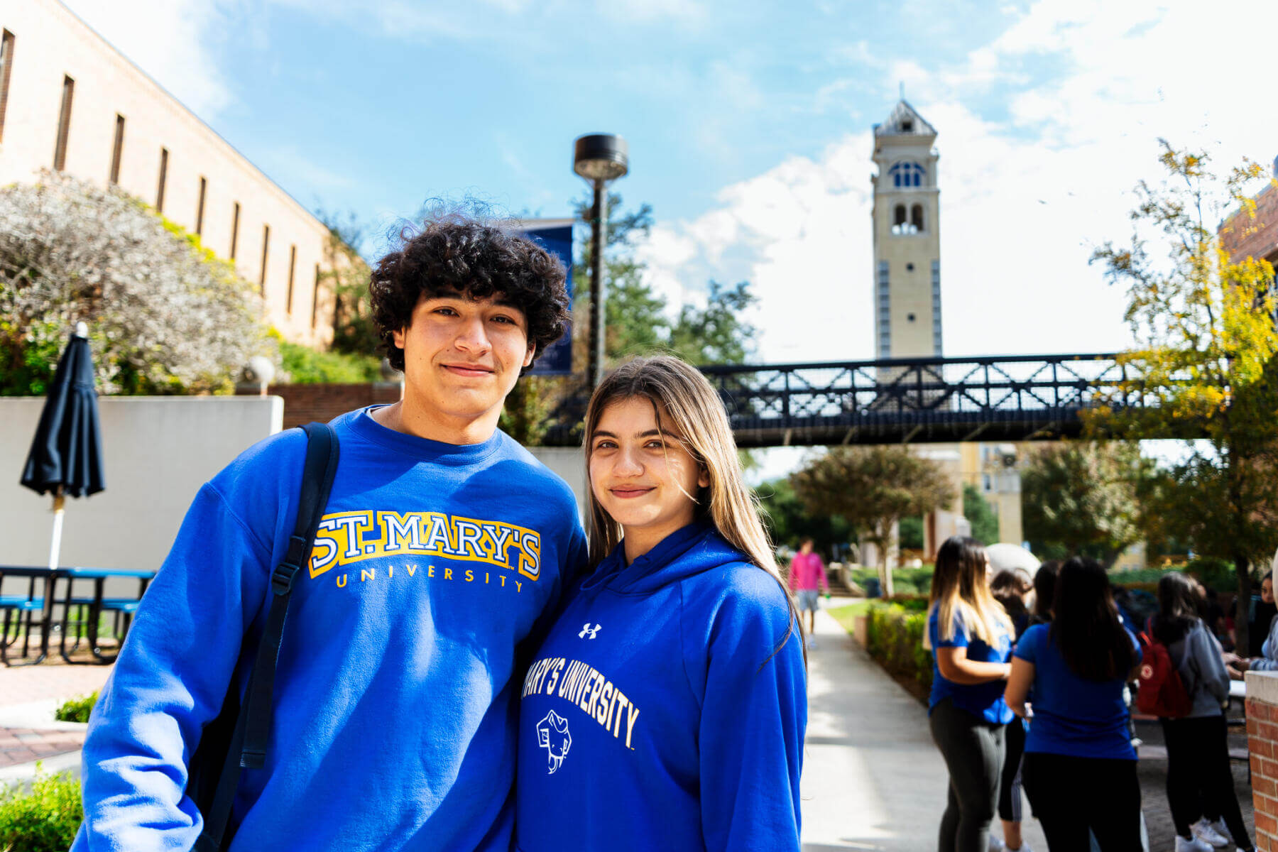 Two students standing in front of Bell Tower wearing matching sweatshirts