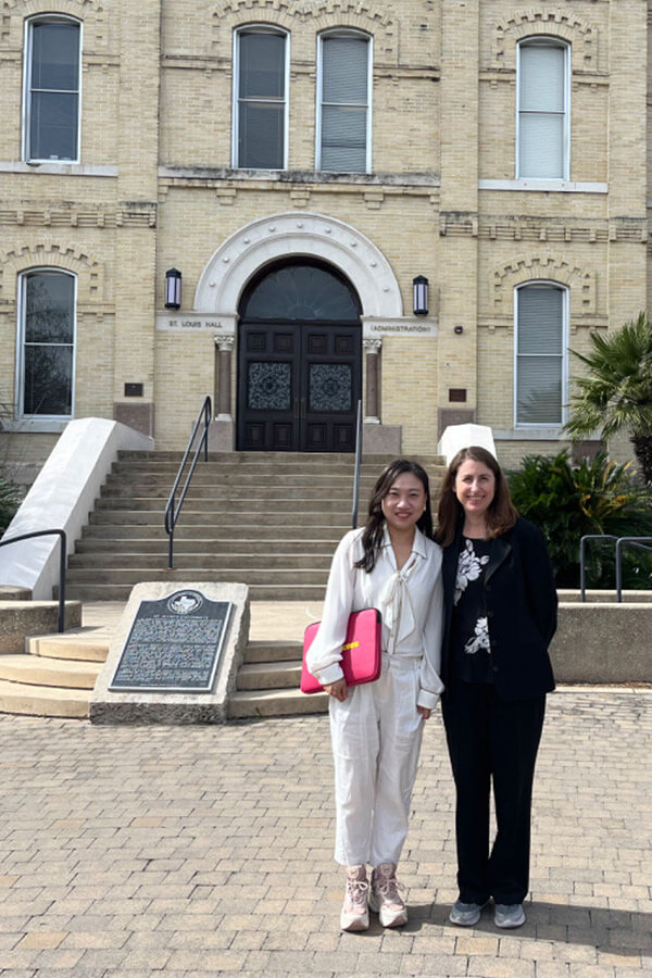 Photo shows Visiting Scholar Yun Weixiao, Law Professor at Changchun Humanities Academy in China, and Kathleen Stevenson, J.D., Assistant Dean for International Programs for the School of Law, visit in front of St. Louis Hall on the St. Mary's University campus.