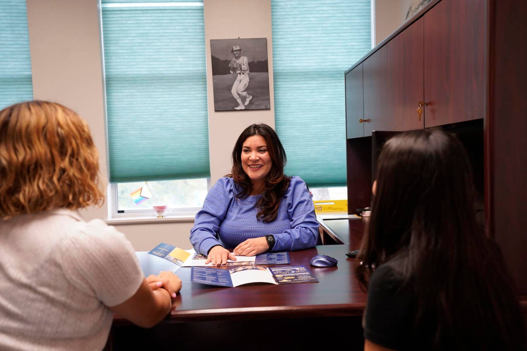 An adviser sits across from a student at a desk discussing scholarship options.