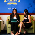 Photo of two students looking at an Ipad in front of St. Mary's E-sports wall-wrap