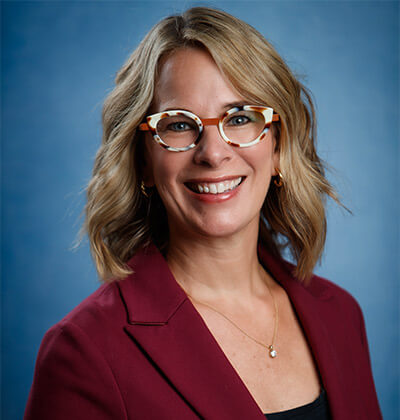 Professional photo of Melissa Shultz wearing red jacket and colorful glasses