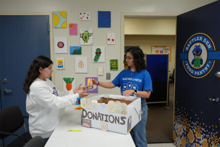 Student assistants Ilianna Baez, left, and Kathya Almanza unloads a box of donations at the Rattler Den in the Center for Life Directions.