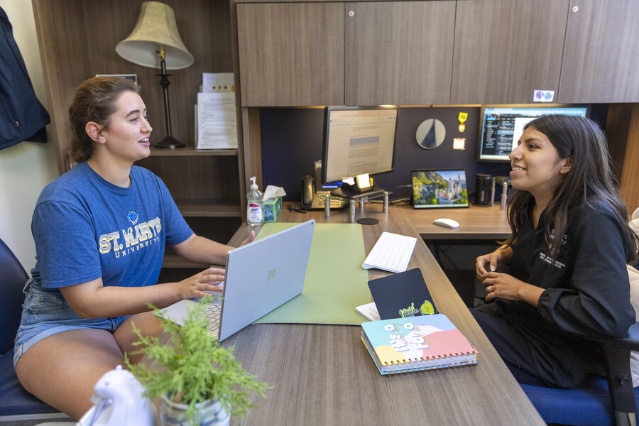 an adviser sits across a desk from a student during their financial aid appointment