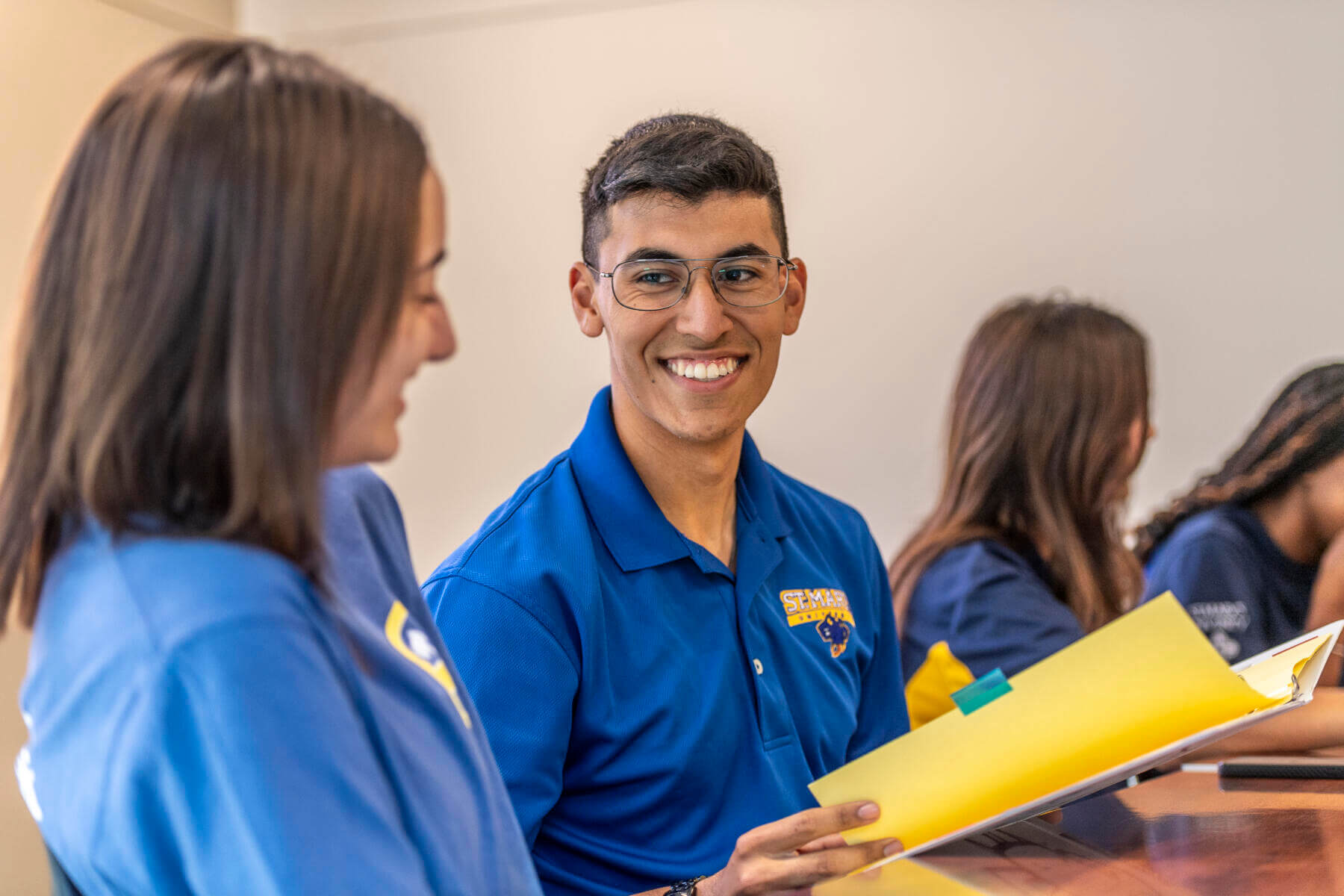 Two students smiling and flipping through a folder.