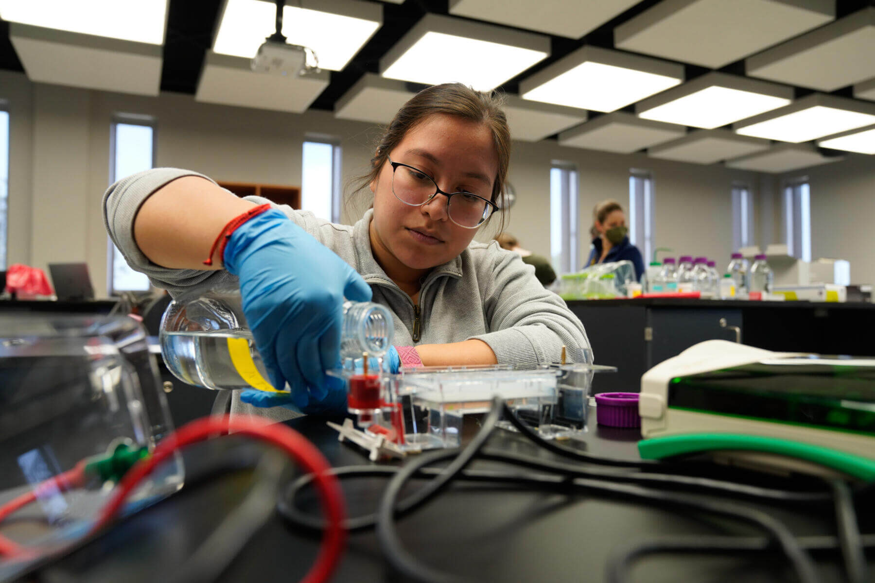 student in a lab pouring a liquid out of a beaker