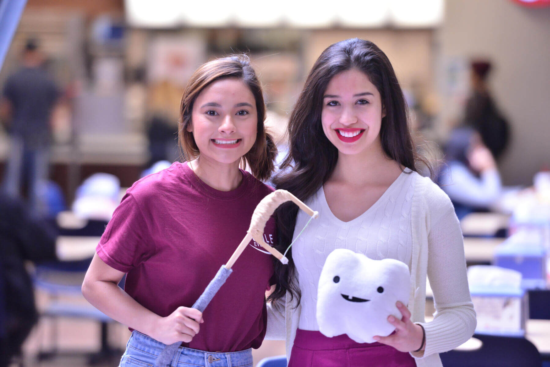 Two students holding a fake giant tooth and floss