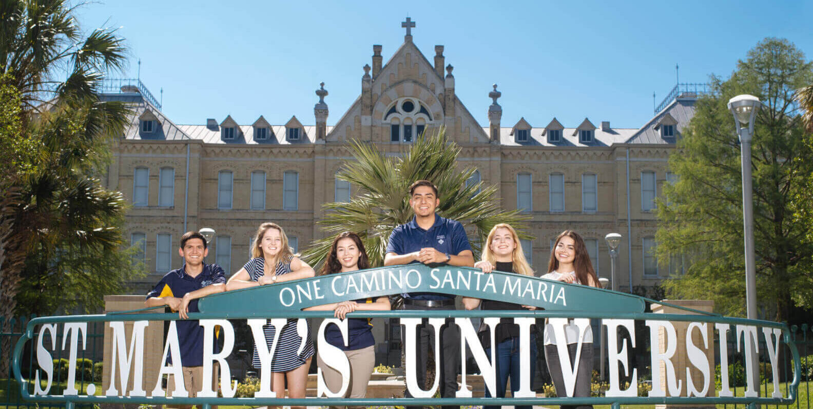 Students stand together behind the St. mary's University sign in front of St. Louis Hall