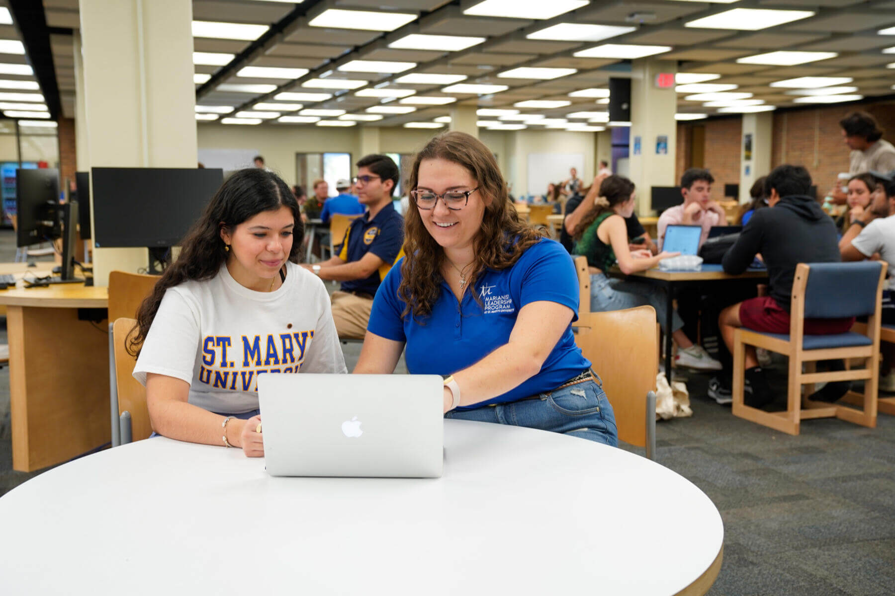Two female students in Blume library commons on computer.