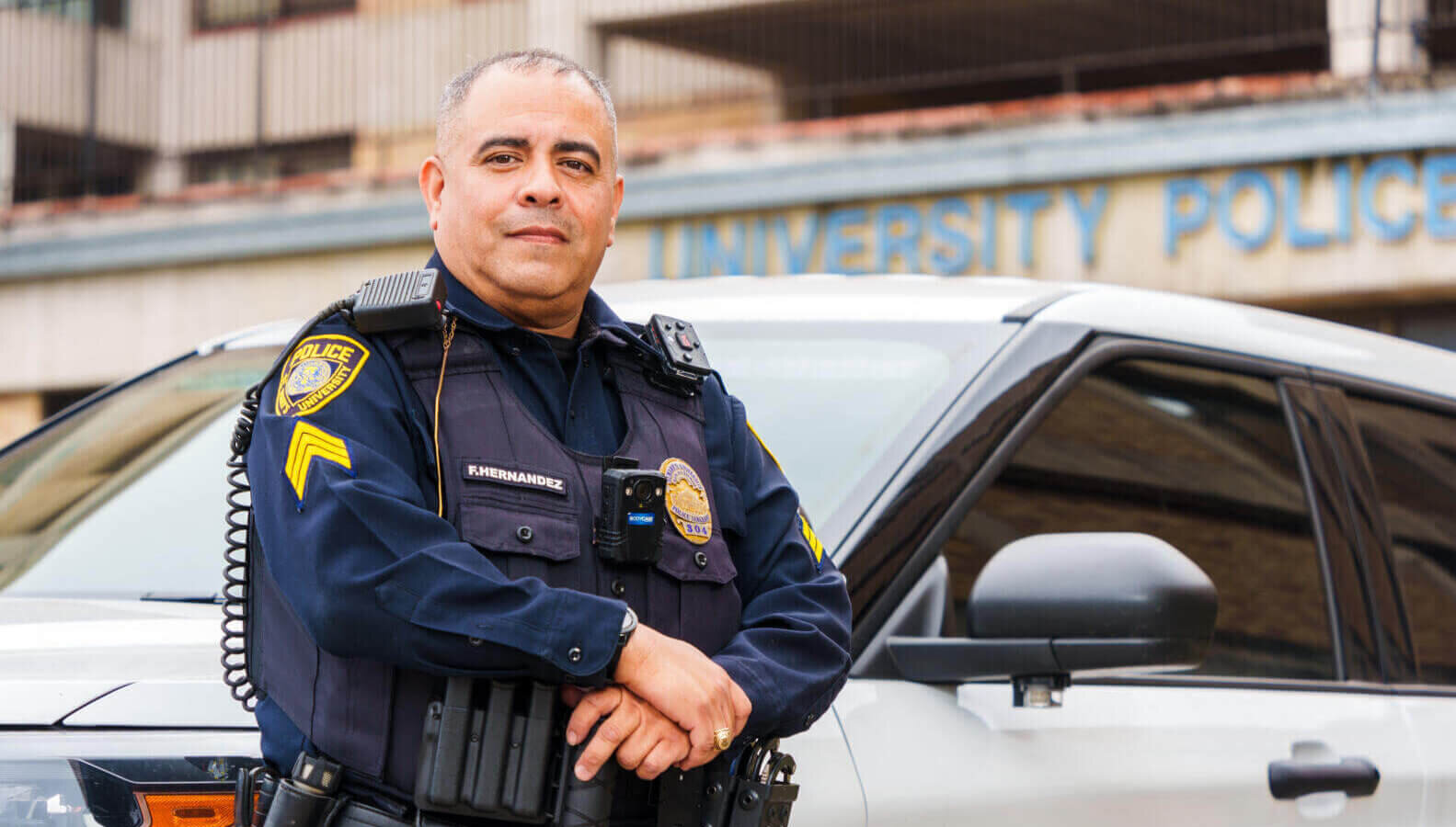 Police Officer standing next to a white car keeping campus parking lots safe.