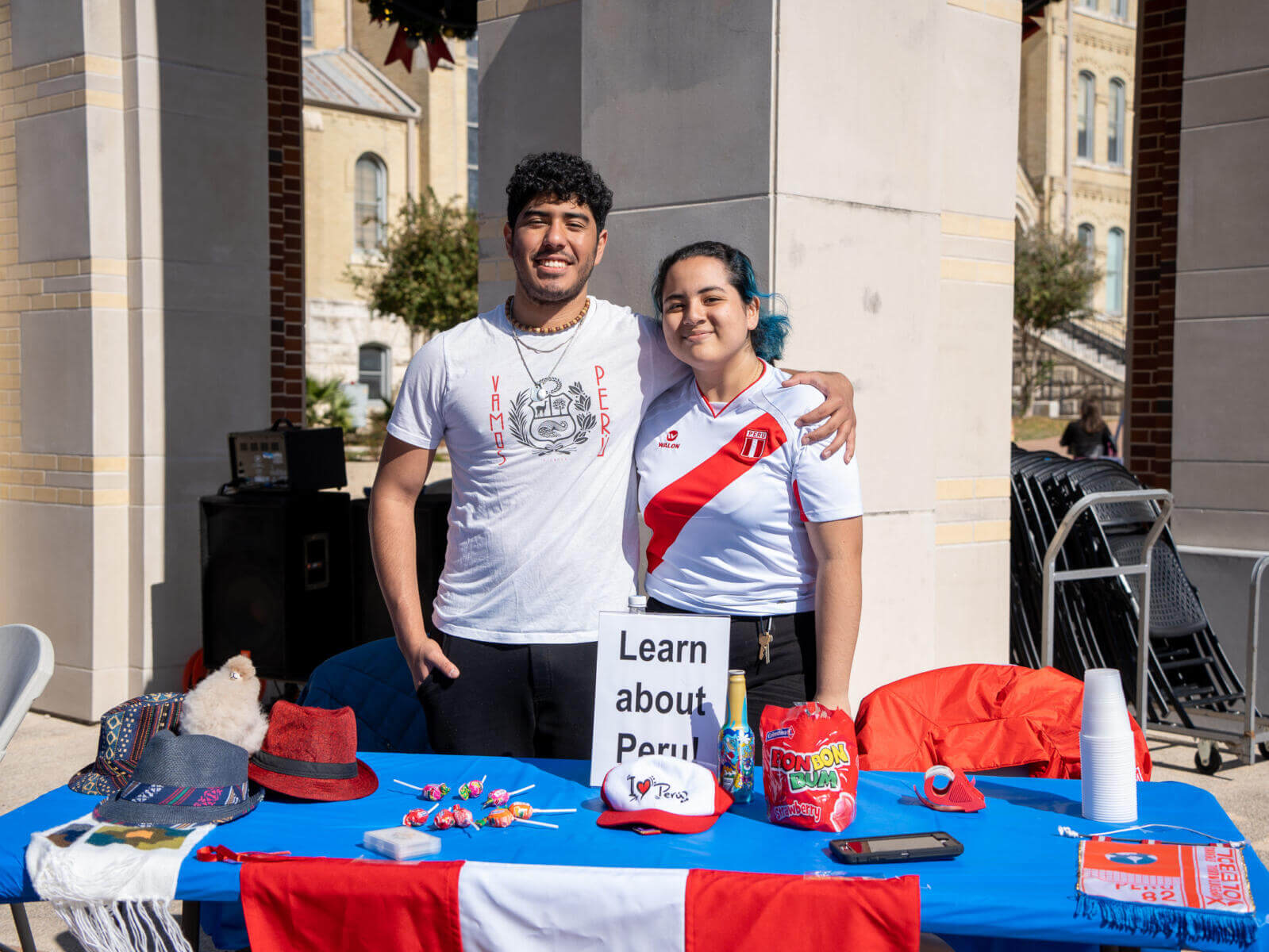 International students during International Education Week pose by a table teaching about Peru