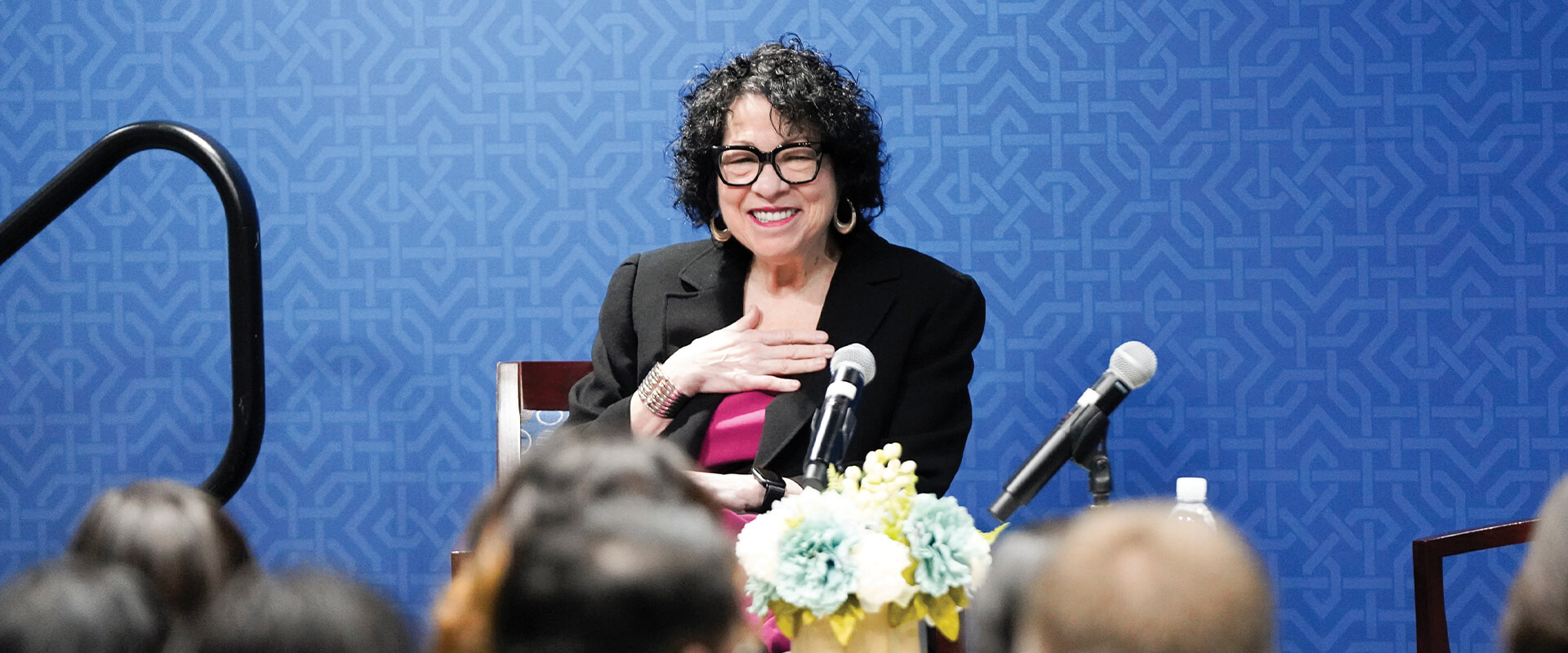 U.S. Supreme Court Justice Sonia Sotomayor speaks to the law school in a conference room. She is wearing a bright pink blouse and a black jacket.