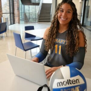 Laurene Robinson sits with her computer and volleyball.