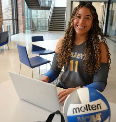 Laurene Robinson sits with her computer and volleyball.