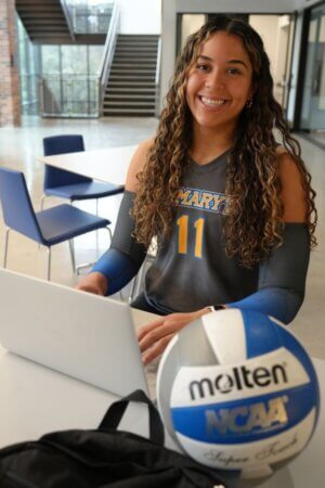 Laurene Robinson sits with her computer and volleyball.
