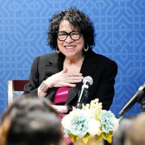 U.S. Supreme Court Justice Sonia Sotomayor speaks to the law school in a conference room. She is wearing a bright pink blouse and a black jacket.