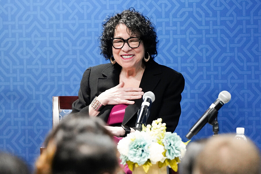 U.S. Supreme Court Justice Sonia Sotomayor speaks to the law school in a conference room. She is wearing a bright pink blouse and a black jacket.
