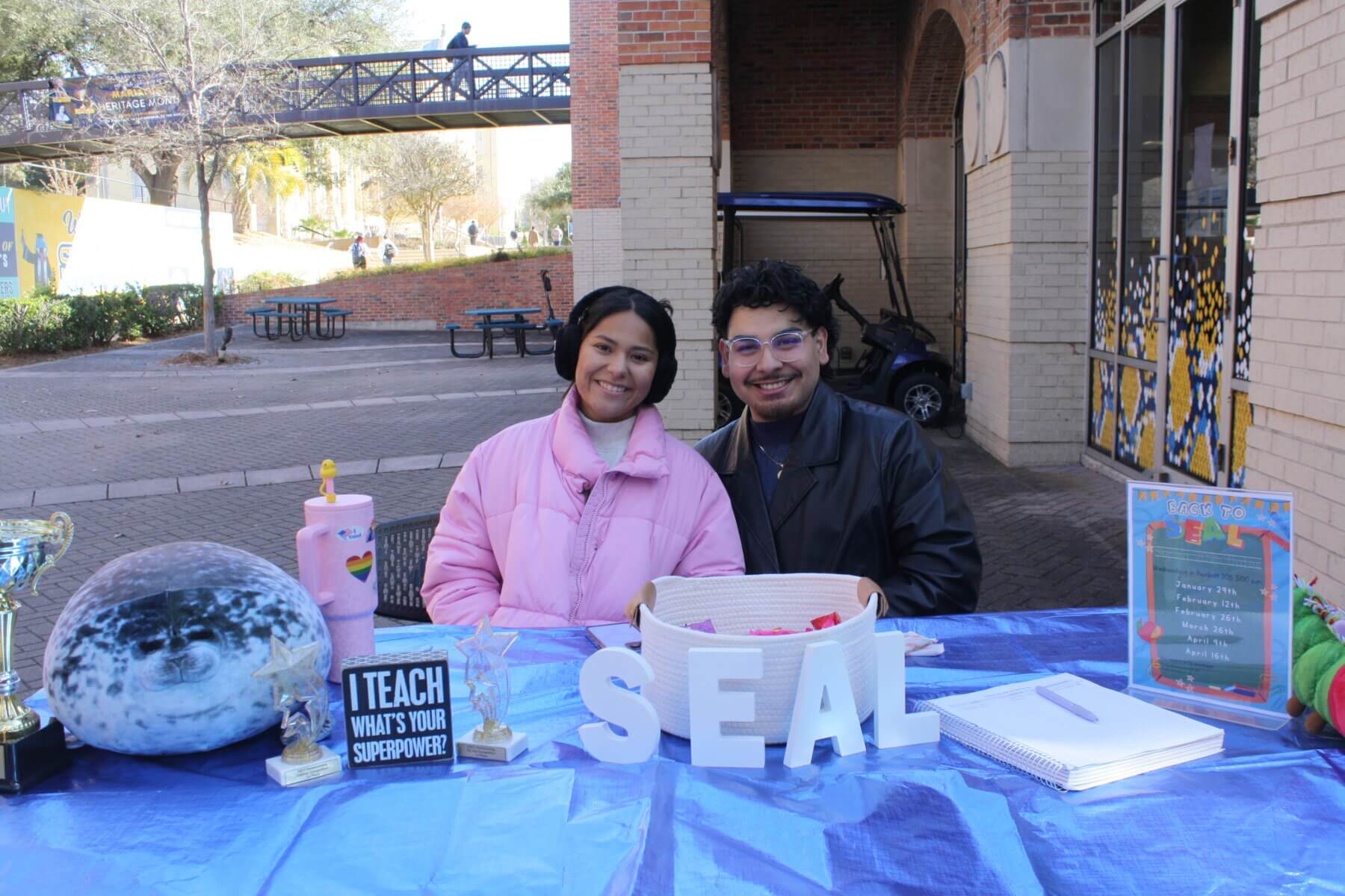 Members of SEAL smile as they sit behind their table