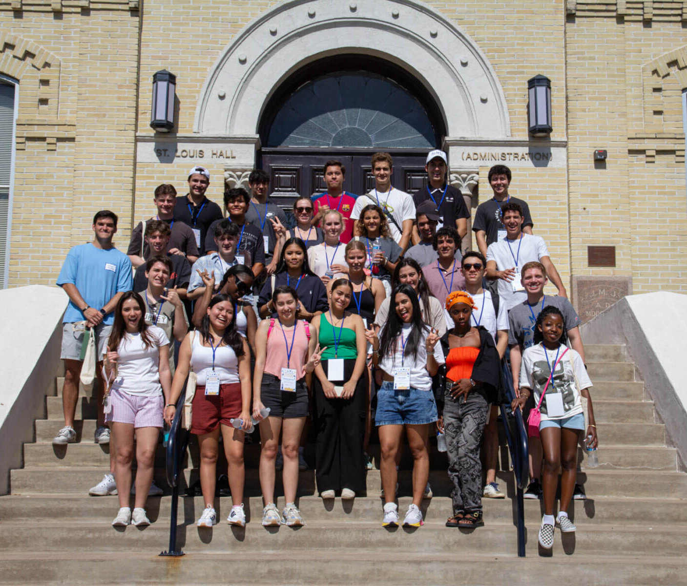 Students take a group photo on the stairs of St. Louis Hall.