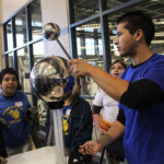 A student from St. Mary's University shows off a science experiment to elementary students.