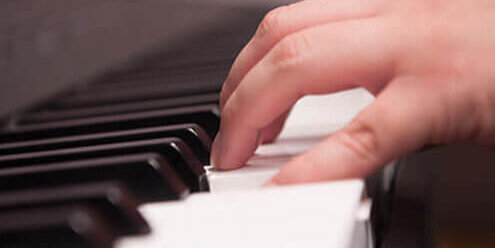 A student's hands on the piano keys.