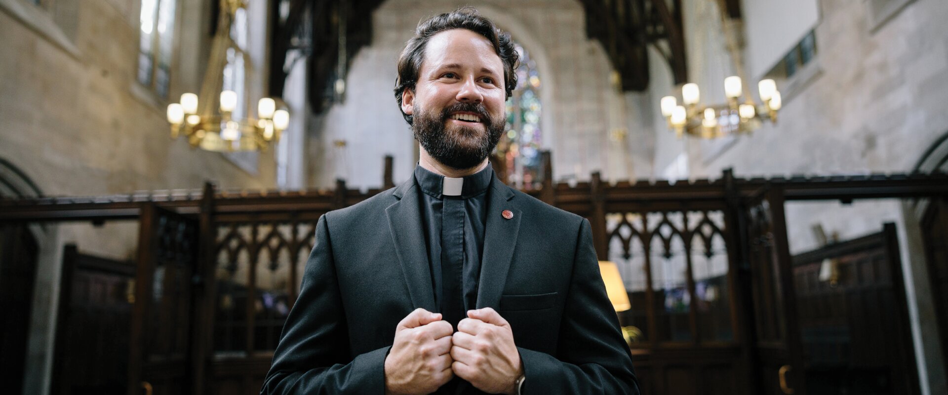William Hayes wears his clerical collar with a dark jacket in the Duane Library at Fordham University in New York.