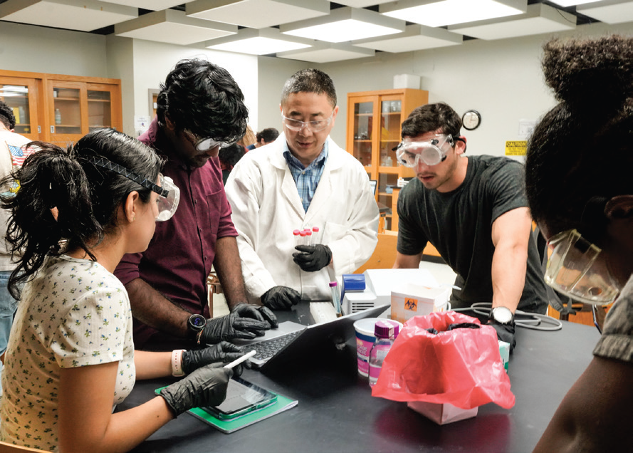 SET students gather around with the professor in the lab as they work together.
