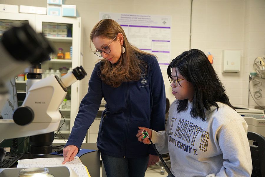 Professor assists students in using lab equipment.